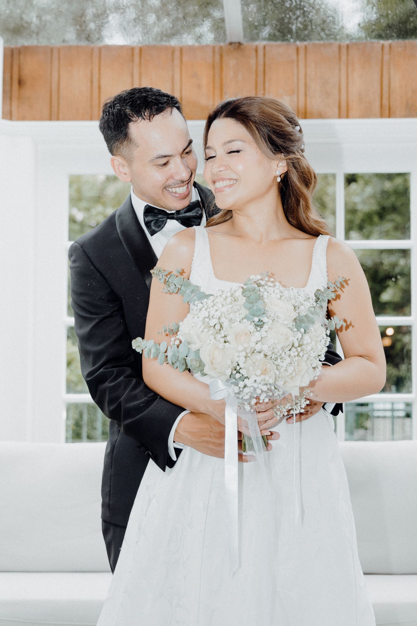 A romantic wedding moment with a couple embracing while holding a blue and white floral bouquet.