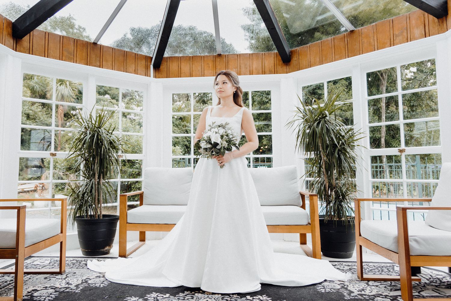 A bridal portrait in a sunlit conservatory captured by Apertured Media Auckland Wedding Photographer.