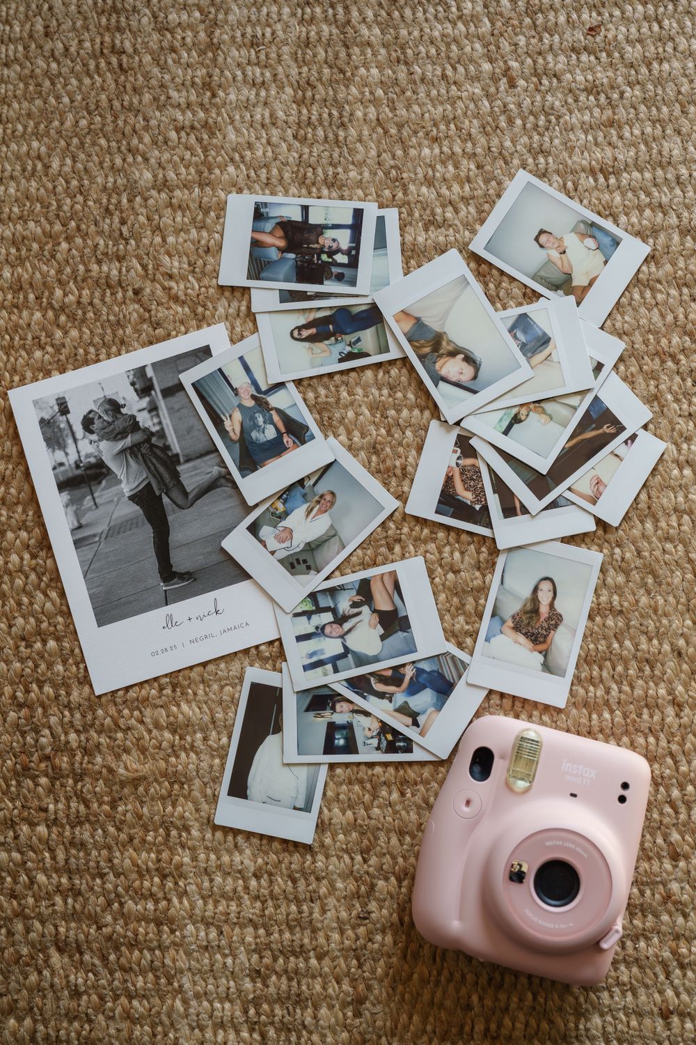 A pink Fujifilm Instax Mini instant camera surrounded by scattered polaroid photos on a beige carpet.