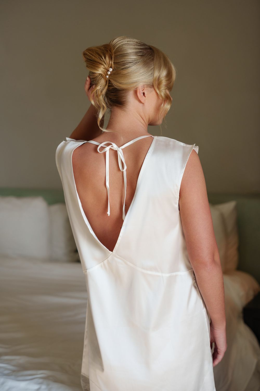 Back view of a white wedding dress with delicate tie detail and open V design.