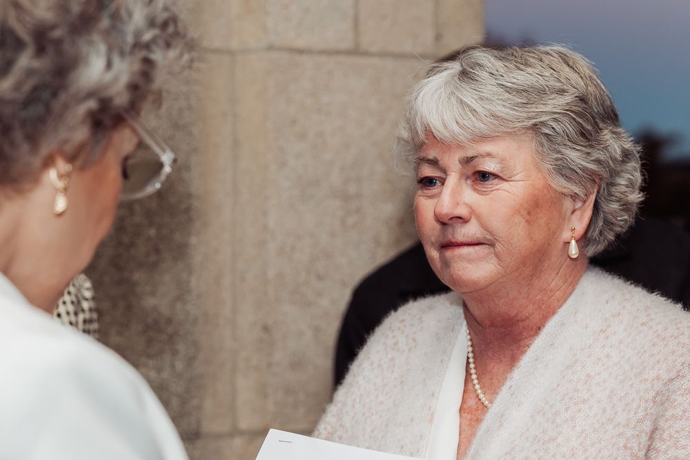 Two people engaged in warm conversation at a formal event with one wearing a soft cream colored sweater.