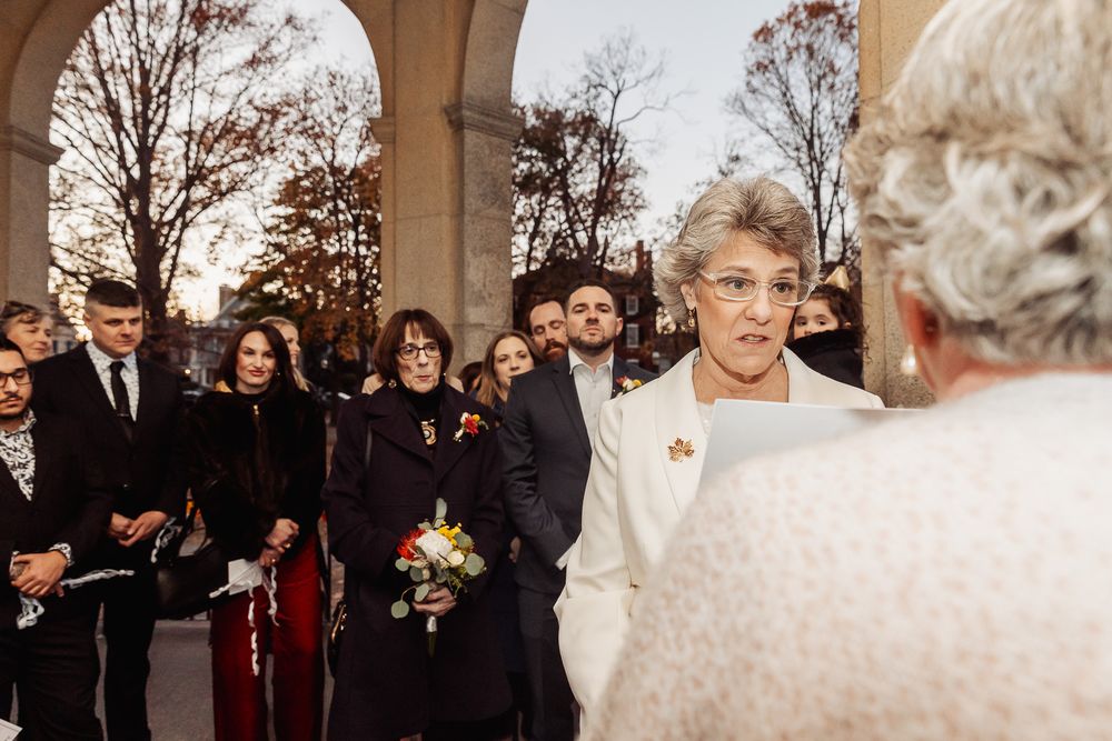 Wedding ceremony guests watching as a couple exchanges vows under stone archways.