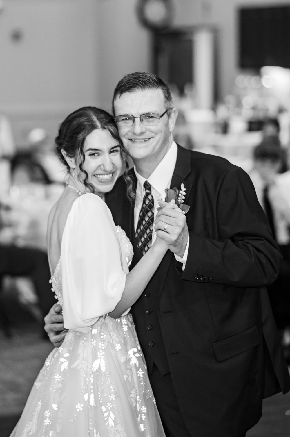 A heartwarming black and white photo of a father-daughter dance at an elegant wedding reception.