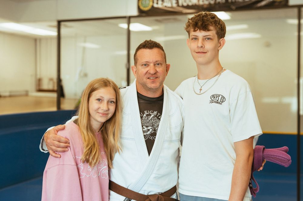 Students and instructors pose together inside a martial arts studio after a training session.
