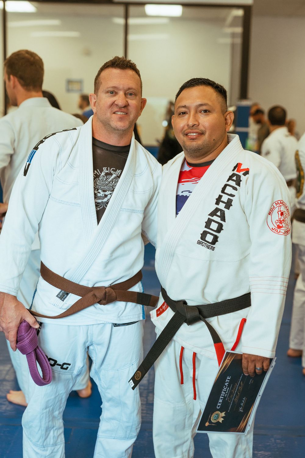 Martial arts students wearing white gis line up on blue mats during a training session.