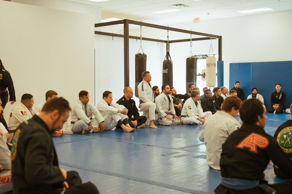 Students practicing martial arts moves on exercise mats in a bright training facility with blue walls.