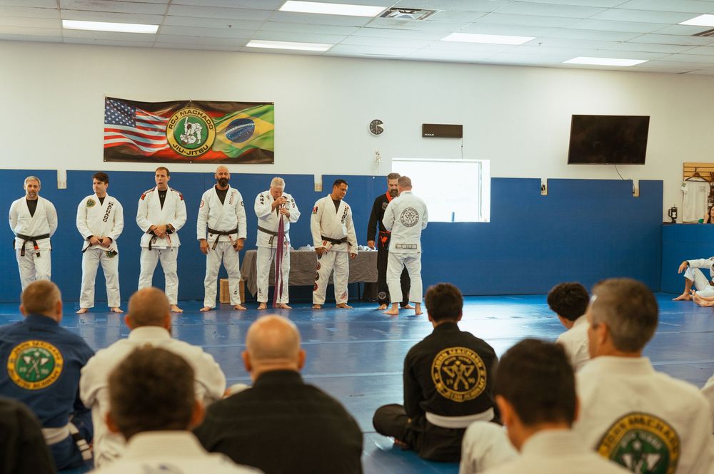 Students line up in white martial arts uniforms while training in a bright dojo with colorful wall decorations.