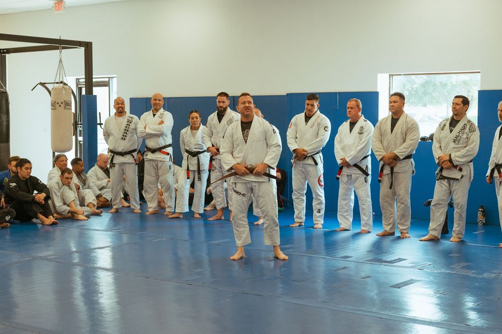 Students gather in white uniforms on blue mats during a martial arts training class at a dojo.