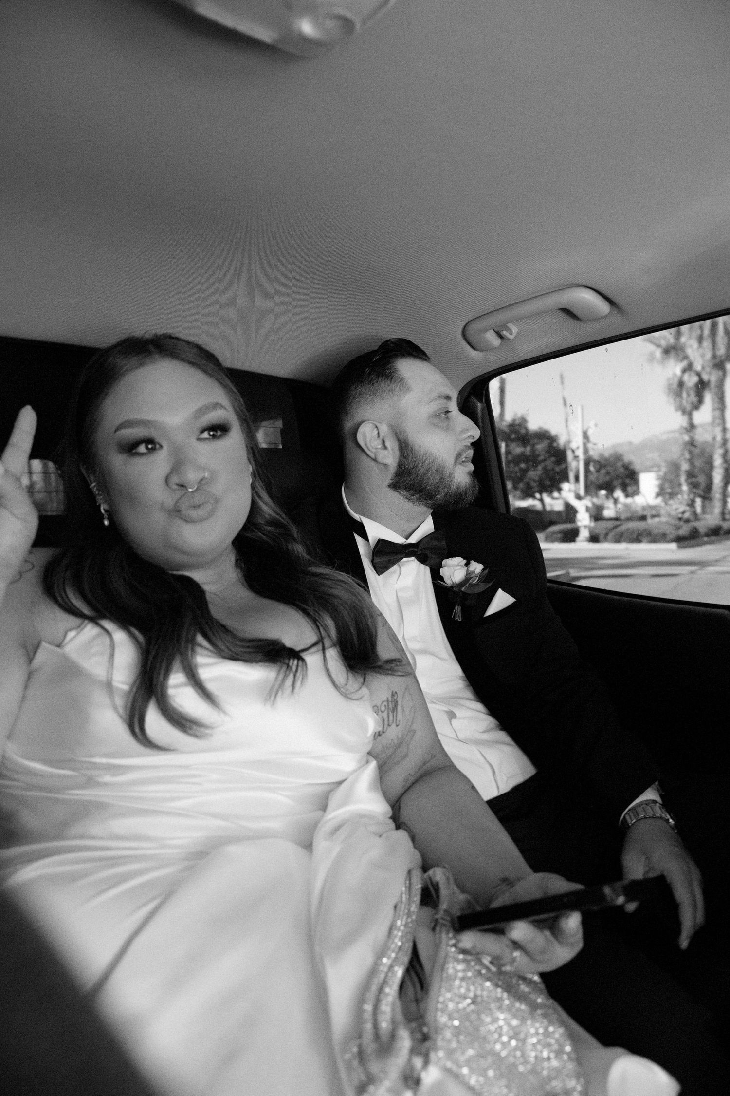 A tender moment captured in black and white of newlyweds sharing the back seat of a car after their wedding ceremony.