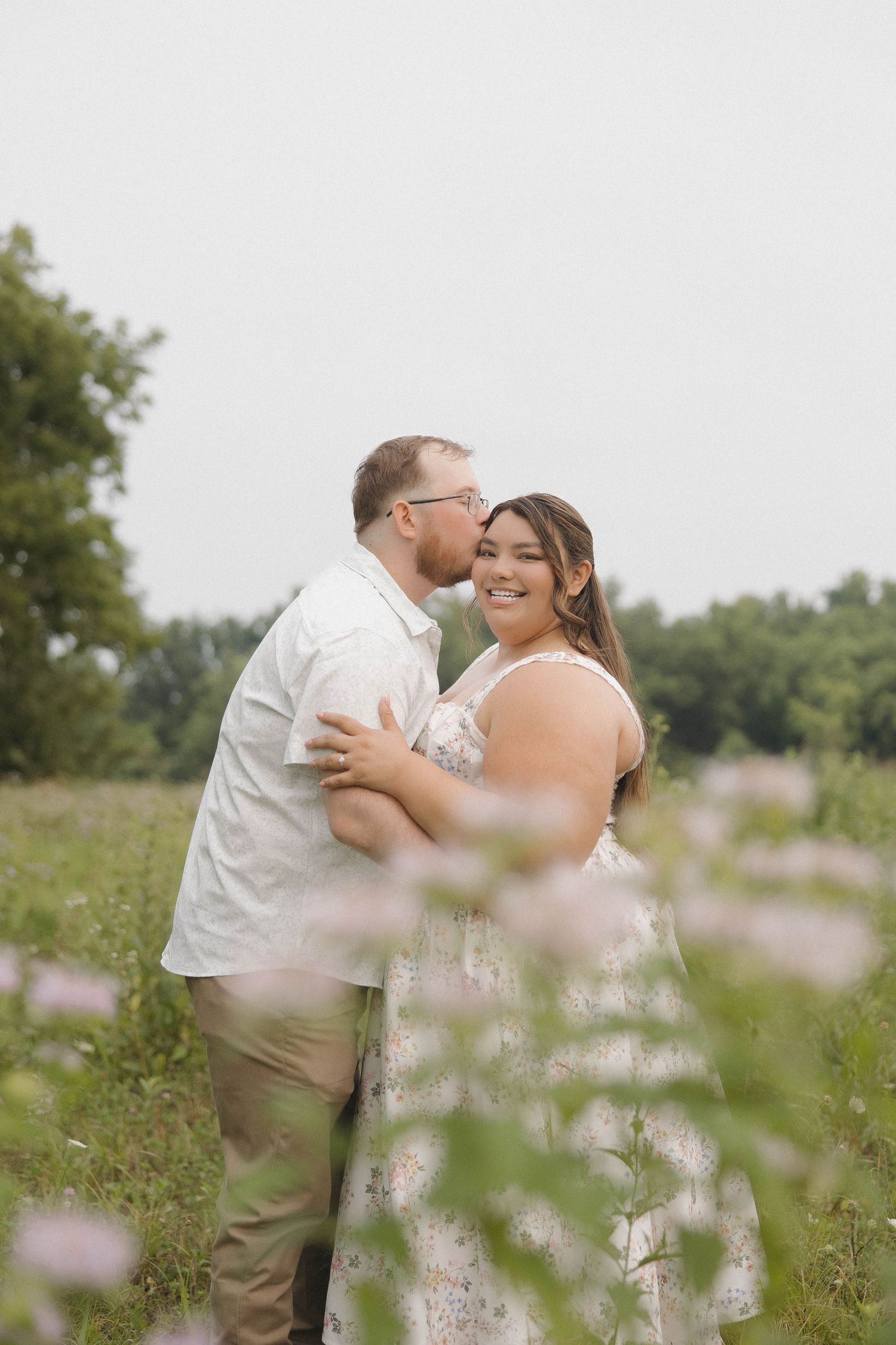 A couple in wedding attire share tender moments together in a blooming wildflower field on their special day.