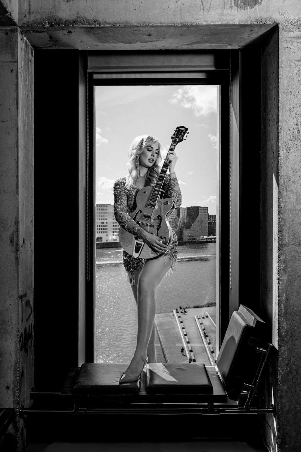 Black and white photo series showing model posing with guitar in industrial window frame setting.