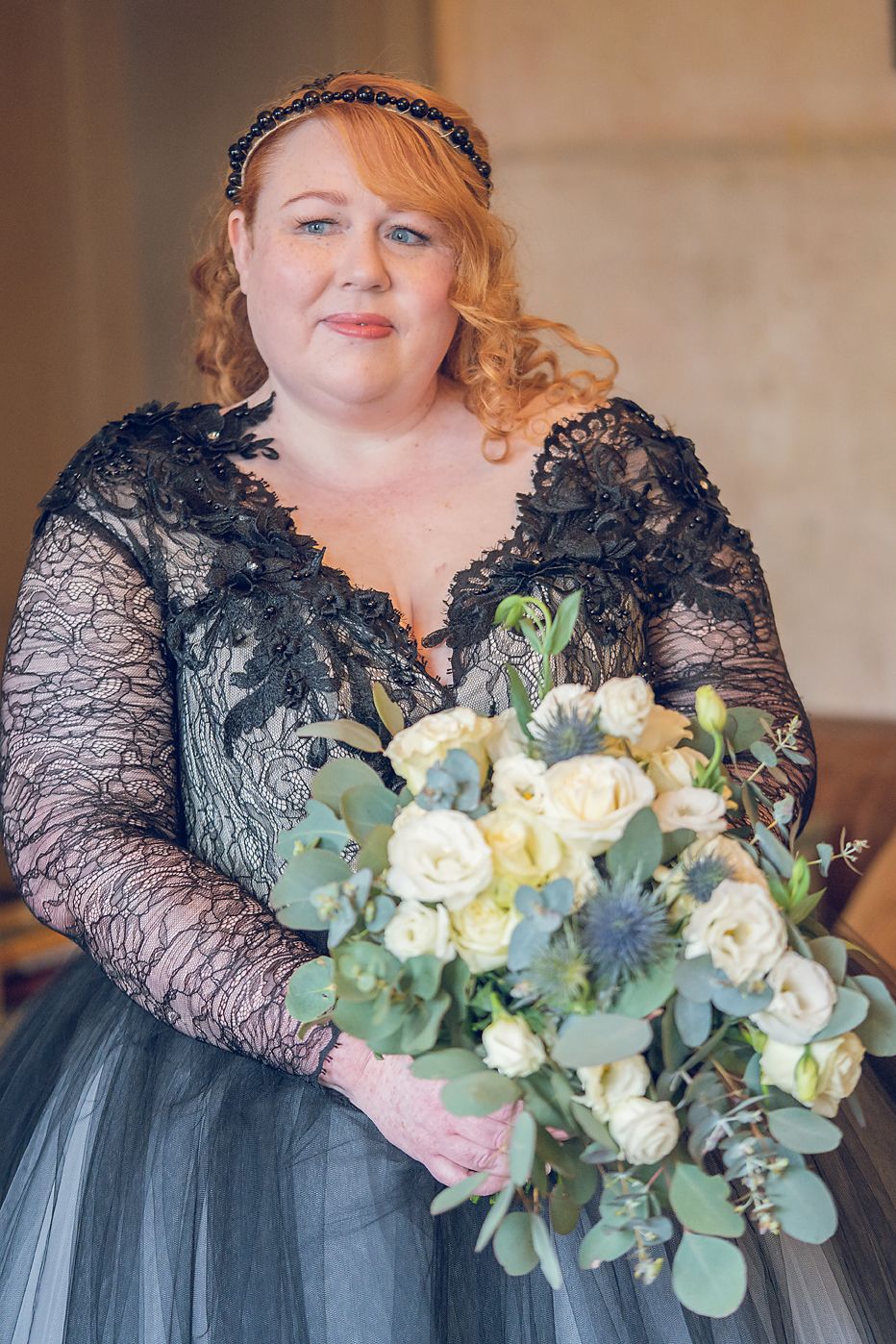 Wedding bouquet in shades of cream and eucalyptus held against a navy lace and tulle dress.