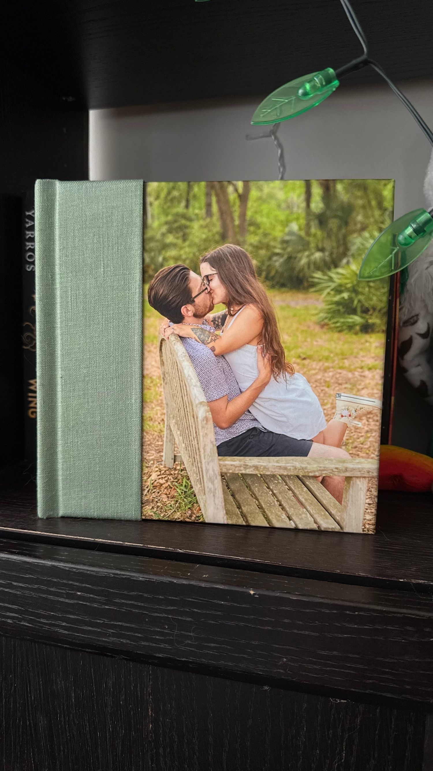 A mint green photo album displaying a romantic outdoor photograph.
