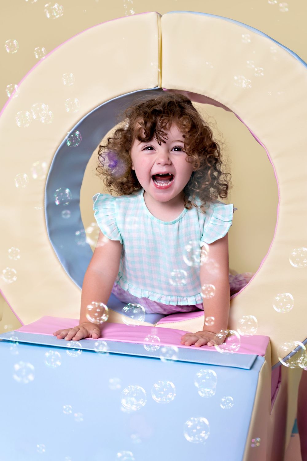 Joyful child surrounded by bubbles playing in a pastel-colored playroom setting.