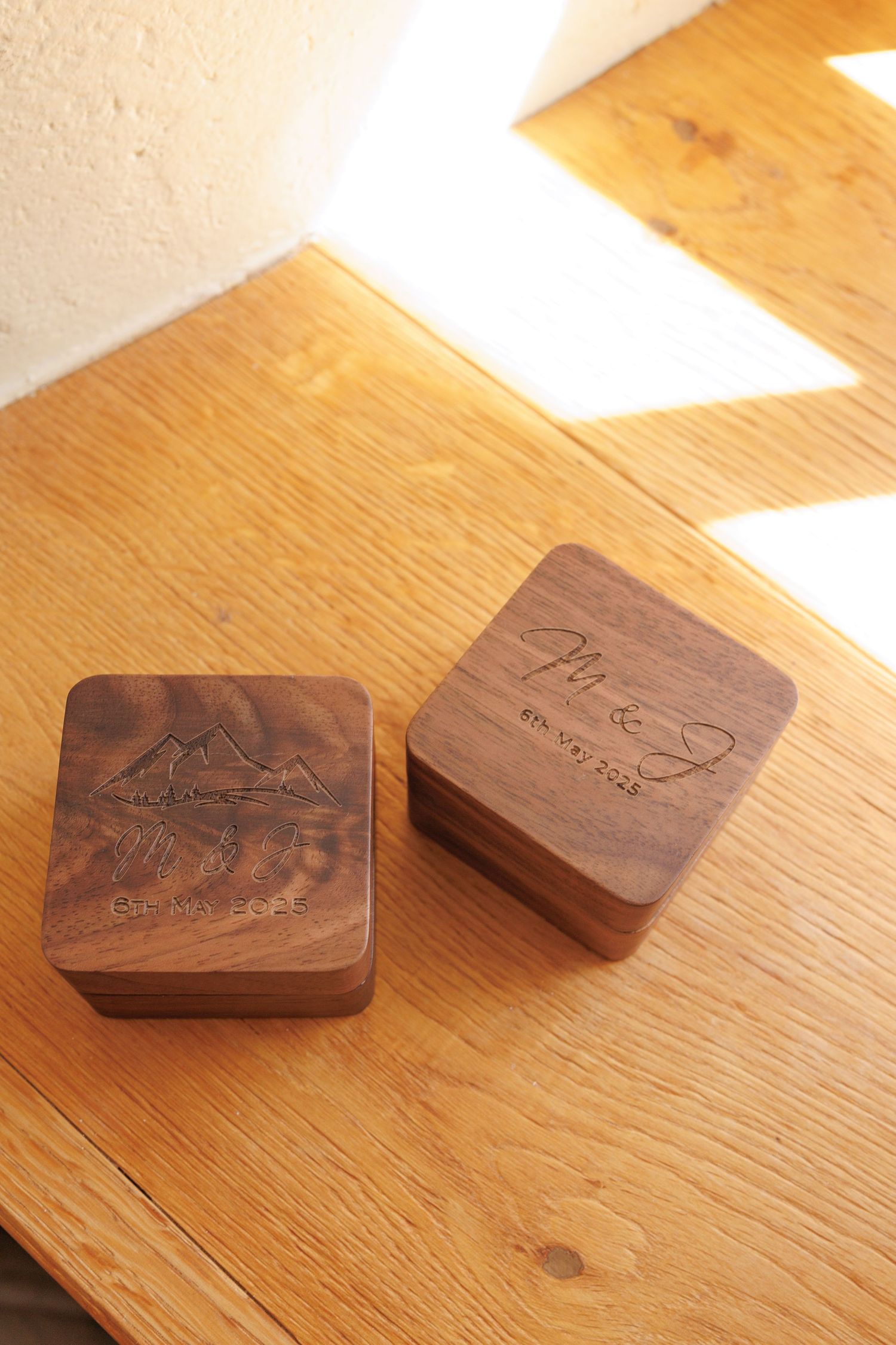 Wooden ring boxes with carved designs are arranged in a row on a light wooden surface.