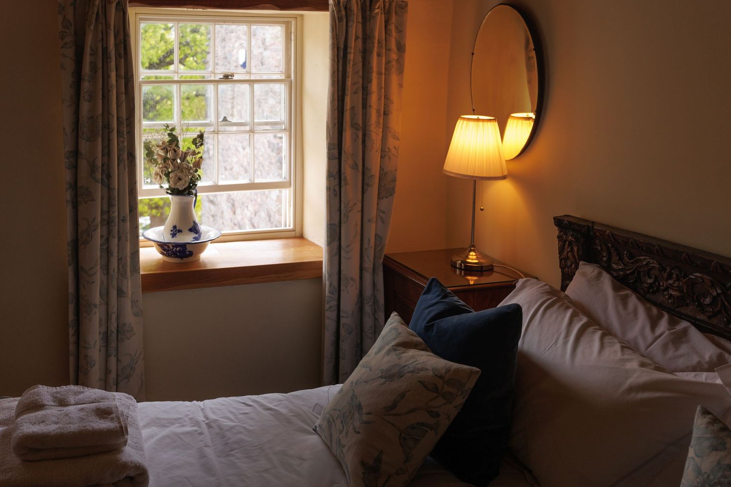 Cozy bedroom interior with natural light streaming through windows and warm ambient lighting.