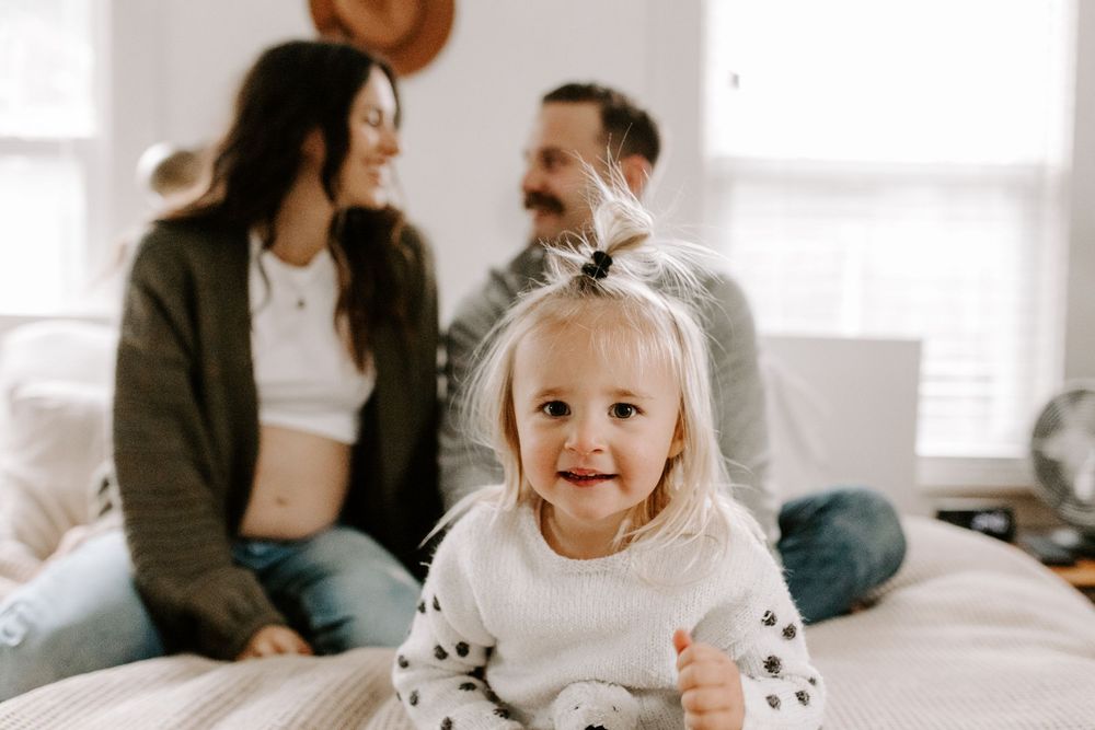A bright family moment captured in a sunlit bedroom with happy expressions.