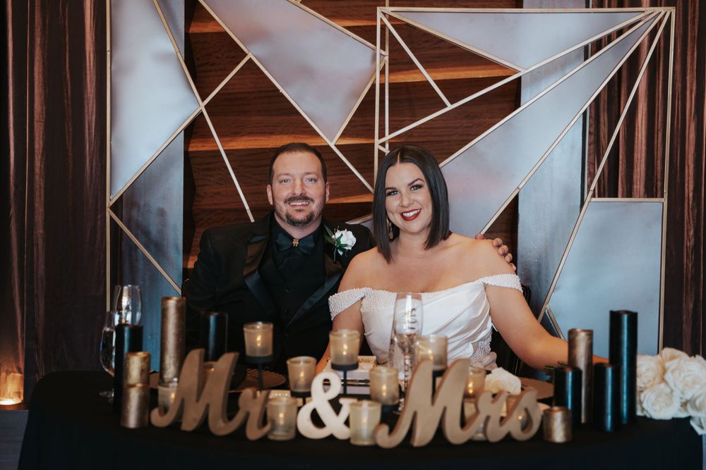 A warm lit rustic wedding reception venue with a decorative 'Mr & Mrs' sign displayed on the wall.