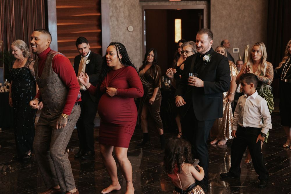 A group of people enjoying a lively dance party in a rustic indoor venue with wooden walls and dim lighting.