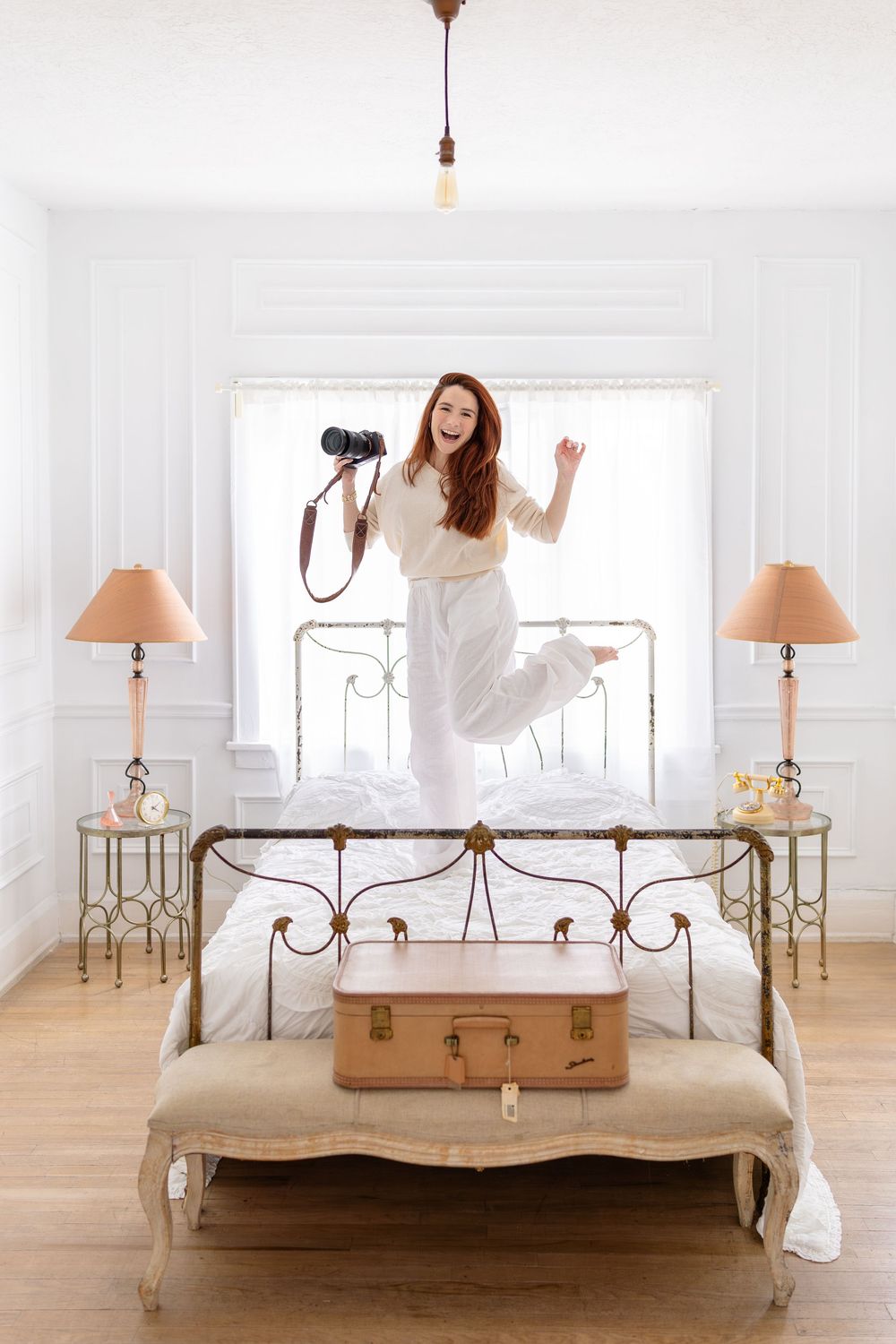 A set of four sequential photos showing someone jumping joyfully on a white wrought iron bed with matching side lamps.