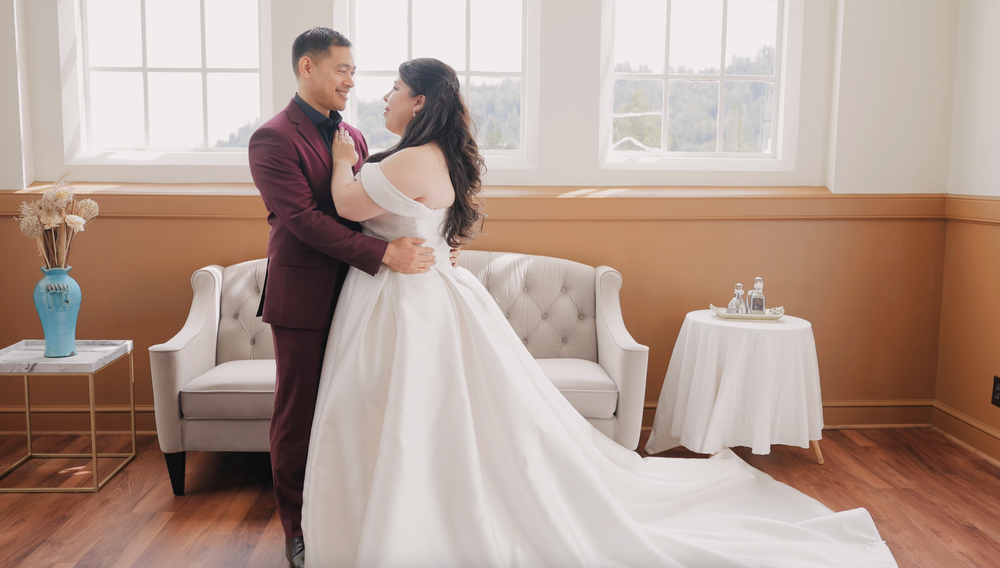 Elegant couple in formal attire sharing romantic moment in sunlit room with vintage decor.