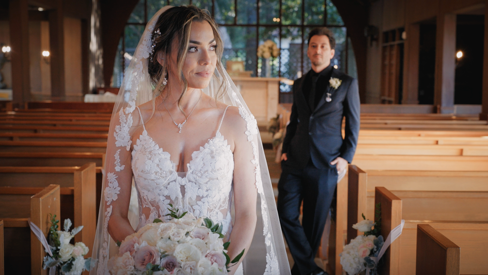 A bride in a lace wedding gown poses in a church sanctuary.