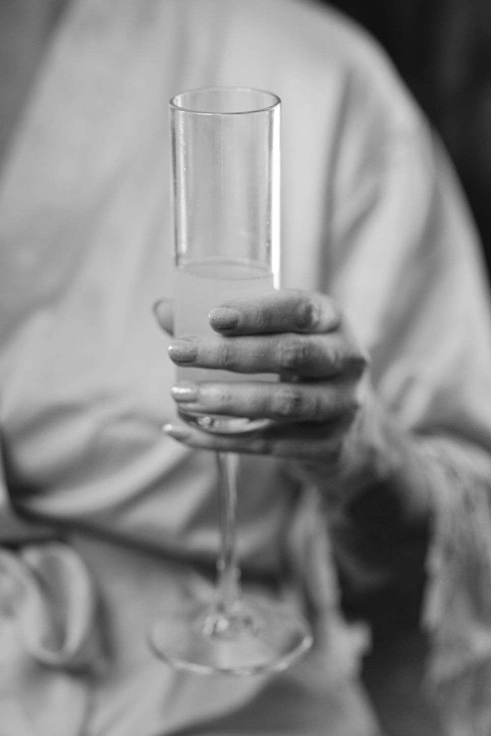 Row of wine glasses held at different angles creating an artistic black and white composition.