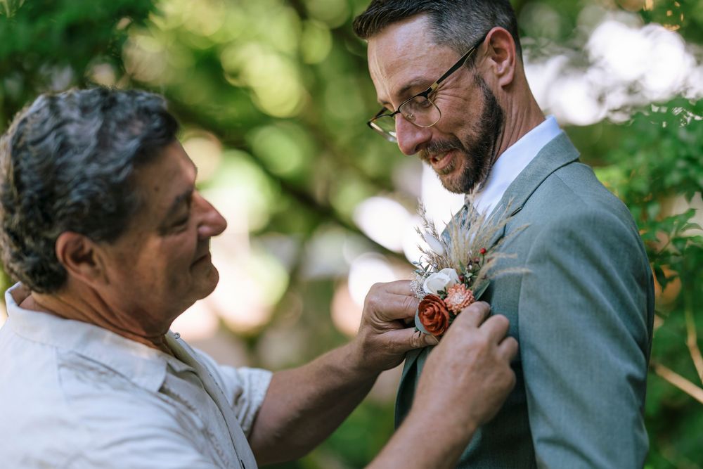 A boutonniere being pinned on a suit jacket during wedding preparations.