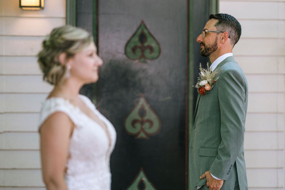 Wedding couple sharing a private moment against a white paneled wall.