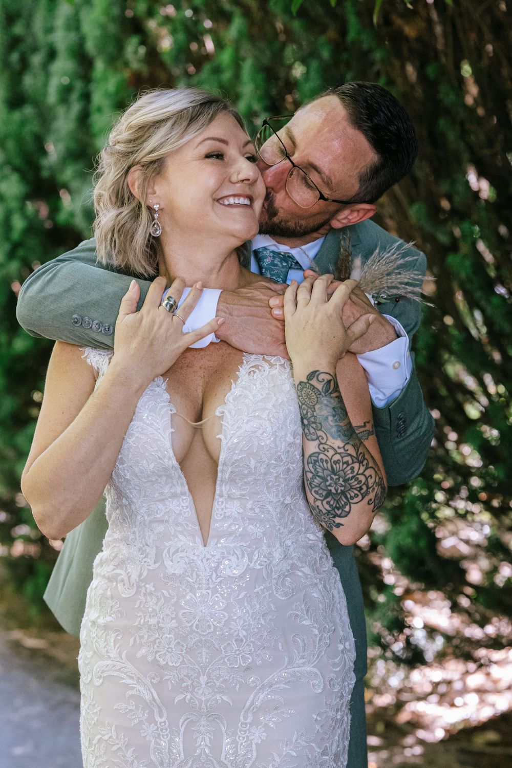 Joyful wedding couple shares intimate moment outdoors with bright smiles and natural backdrop.