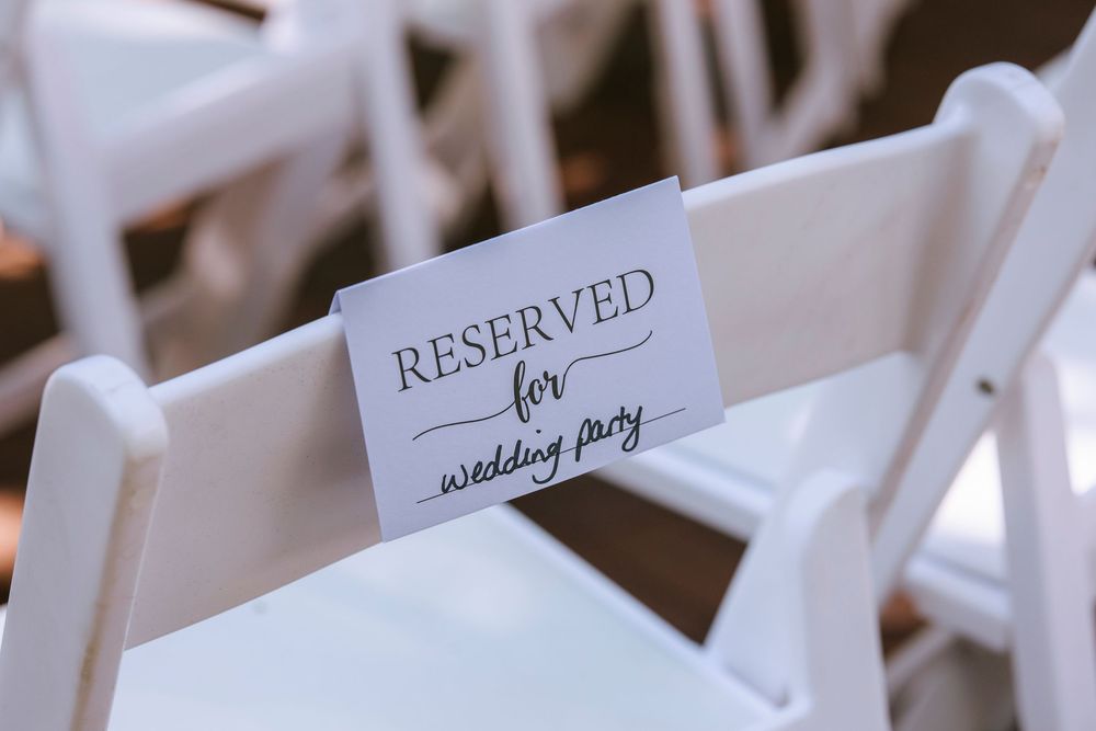 White folding chair with reserved sign for wedding party seating.