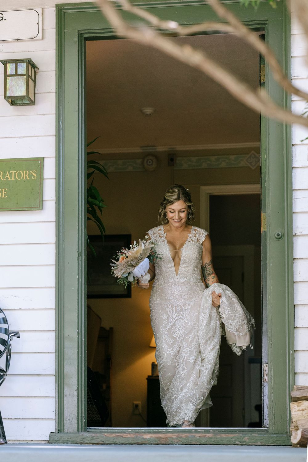 A bride in a lace wedding dress emerges through three successive doorframes of a white porch entrance.