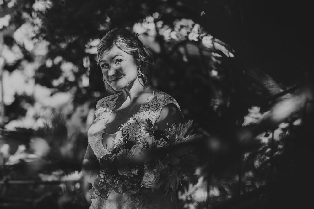 Artistic black and white portrait showing dappled sunlight through trees creating a dreamy atmosphere.