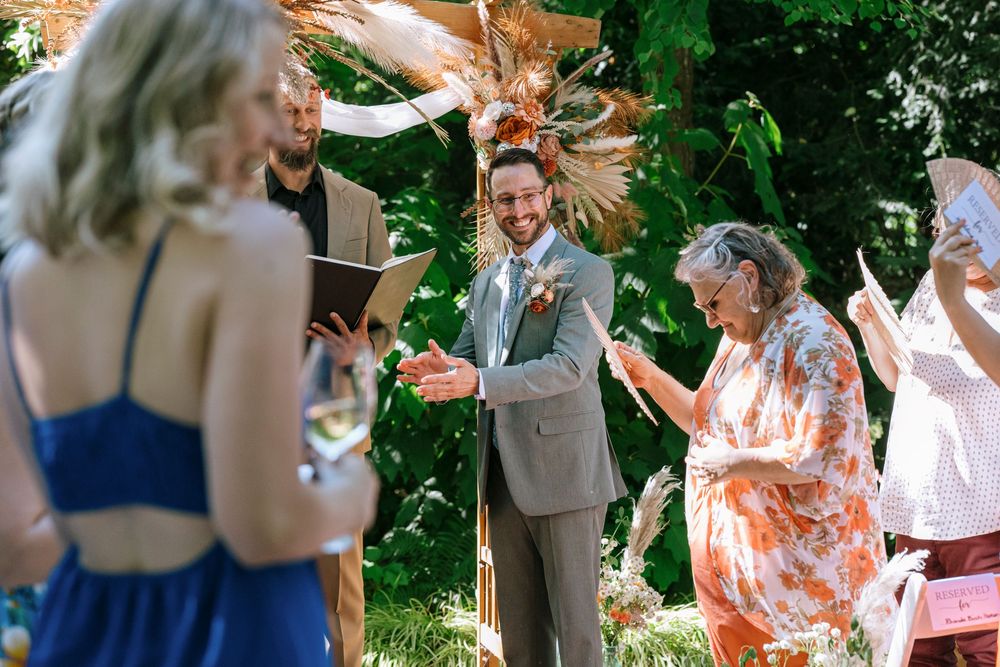 A small group enjoys an outdoor gathering in a garden with joyful dancing and celebratory movements.