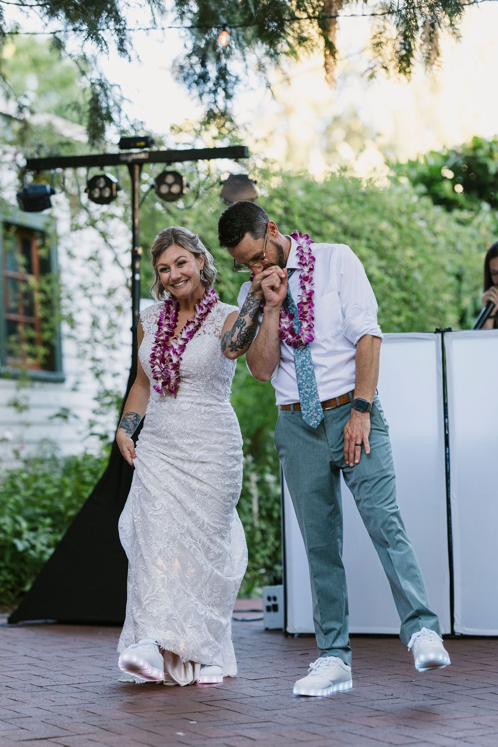 A couple dances together wearing Hawaiian leis during a wedding celebration.