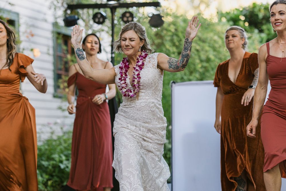 A wedding party poses together outdoors in warm brown and rust-colored dresses during a joyful photo session.