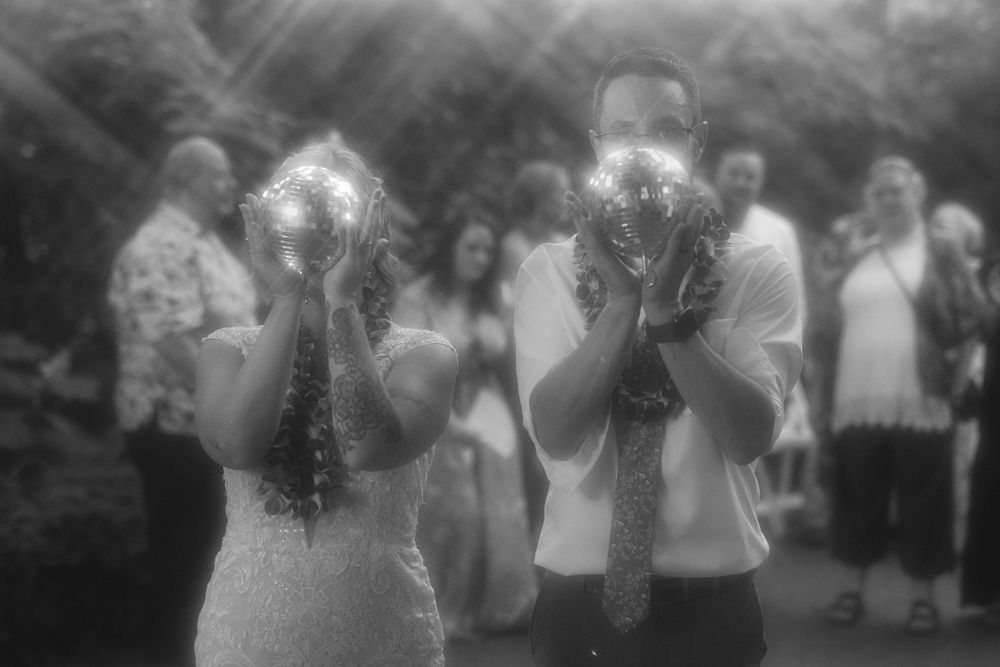 Two photographers take pictures with vintage cameras at an outdoor gathering in a black and white photograph.
