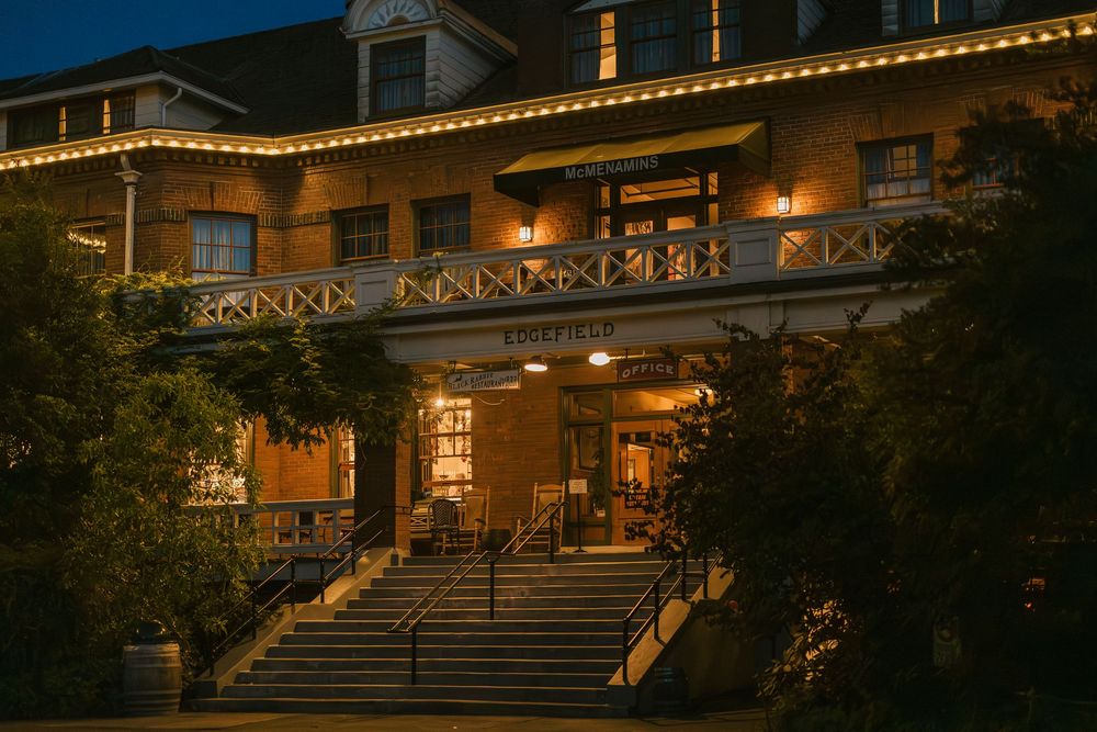 Historic inn with warmly lit facade and grand staircase entrance decorated with string lights at dusk.