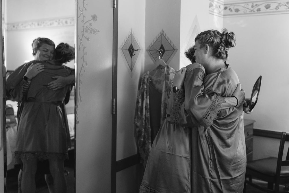 Black and white photo showing silhouettes of people getting ready in a room with natural light.