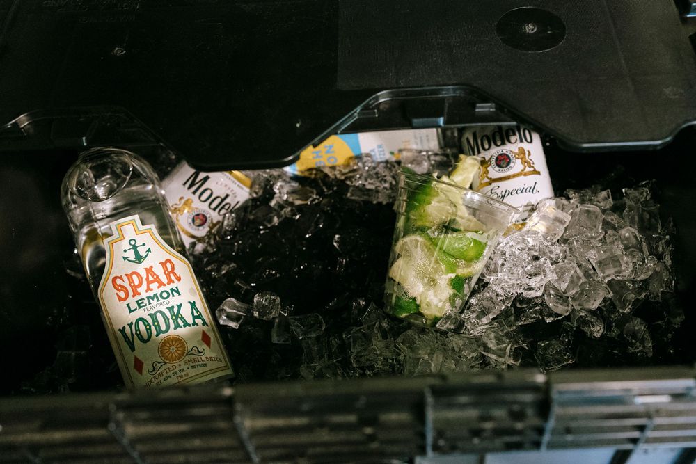 Collection of empty glass bottles and drink containers on dark surface.