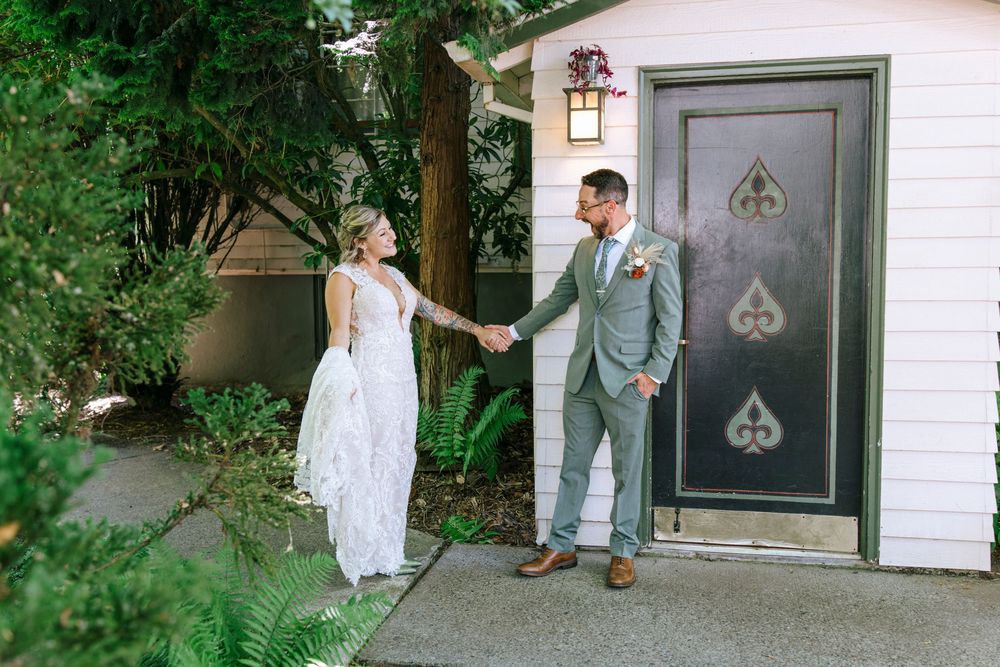 Wedding moment captured in front of a white garage door with spade emblem among garden landscaping.