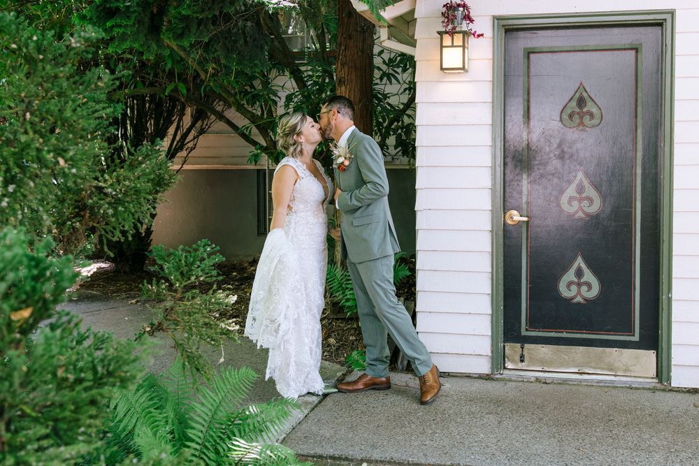 Newlyweds share intimate moment by decorated black door with spade designs.