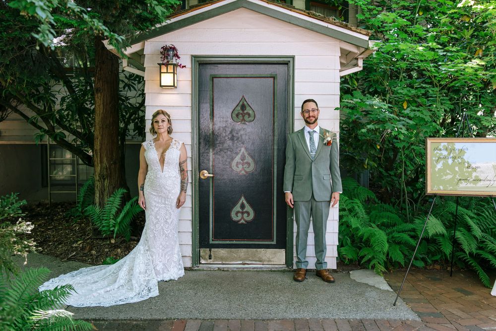 Elegant wedding couple photos taken in front of a house with a dark door and green foliage.