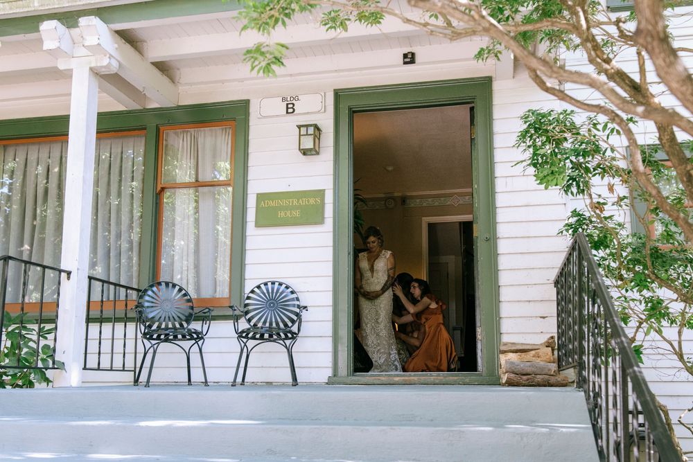 White porch of a traditional administrative building with black wrought iron benches and green trim details.
