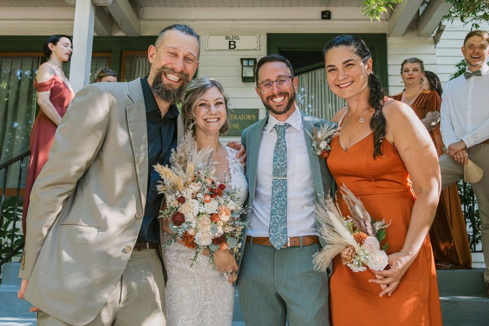 Wedding party members pose together on porch in coordinated attire.