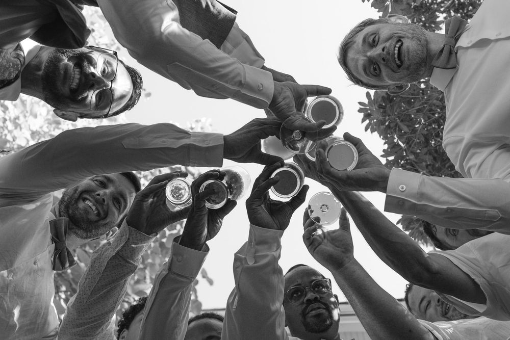 Black and white view from below of friends toasting with drinks in a circle.