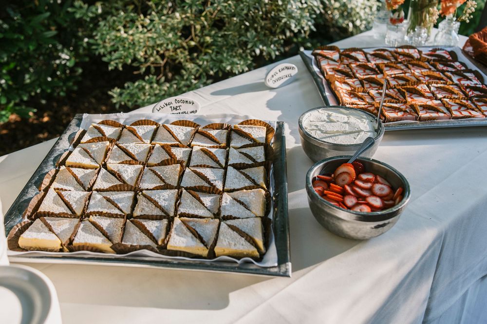 A tiered pie display with various pastries and baked goods arranged on wooden stands at an elegant catering event.