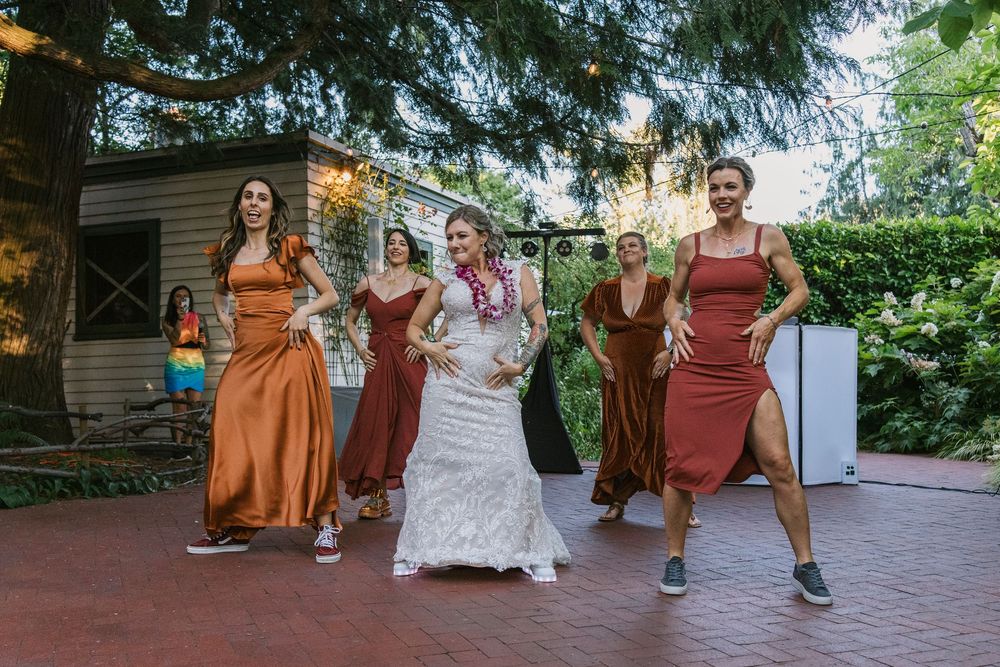 Group performs coordinated dance moves on a paved outdoor patio during a celebration.