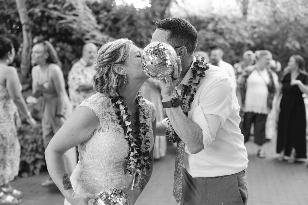 Wedding guests dancing together at outdoor garden reception celebration in black and white photo.