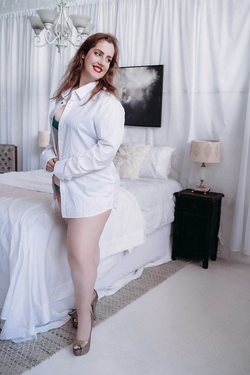 Interior bedroom scene with white decor featuring someone in an oversized white shirt and animal print heels.